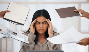 woman sitting at desk with hands on head