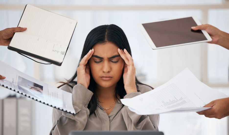 woman sitting at desk with hands on head